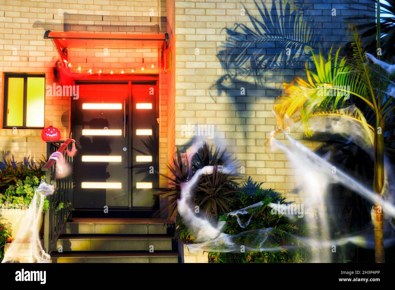 Entrée à une maison résidentielle décorée pour Halloween avec des lumières, des toiles, des araignées, de la citrouille et des fantômes. Banque D'Images