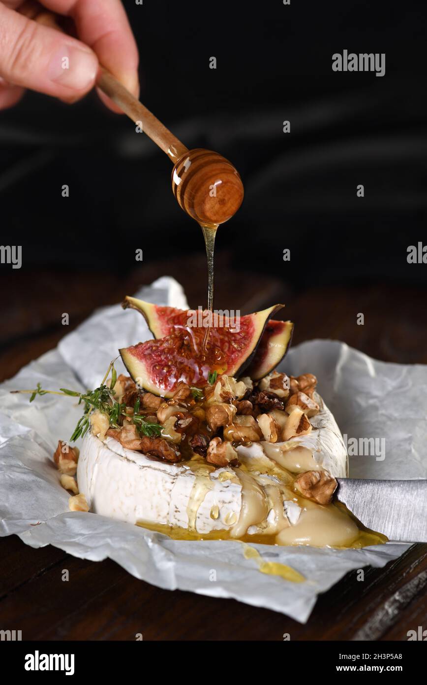 Camembert cuit avec des noix et du miel, des tranches de figues et de thym. Banque D'Images