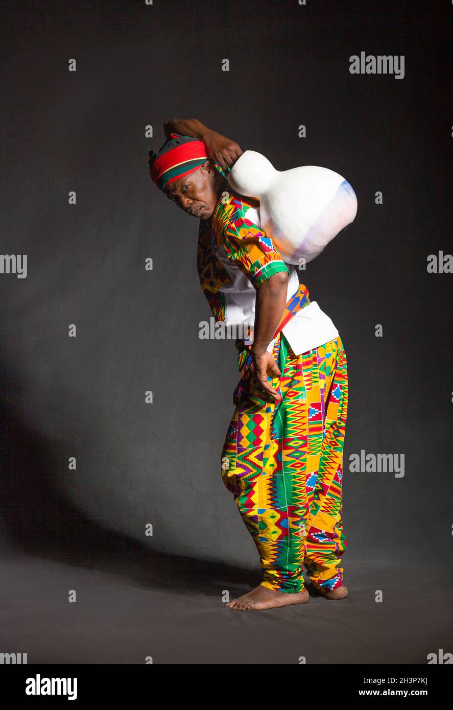 Homme africain dans les vêtements traditionnels souriant, sur fond gris Banque D'Images