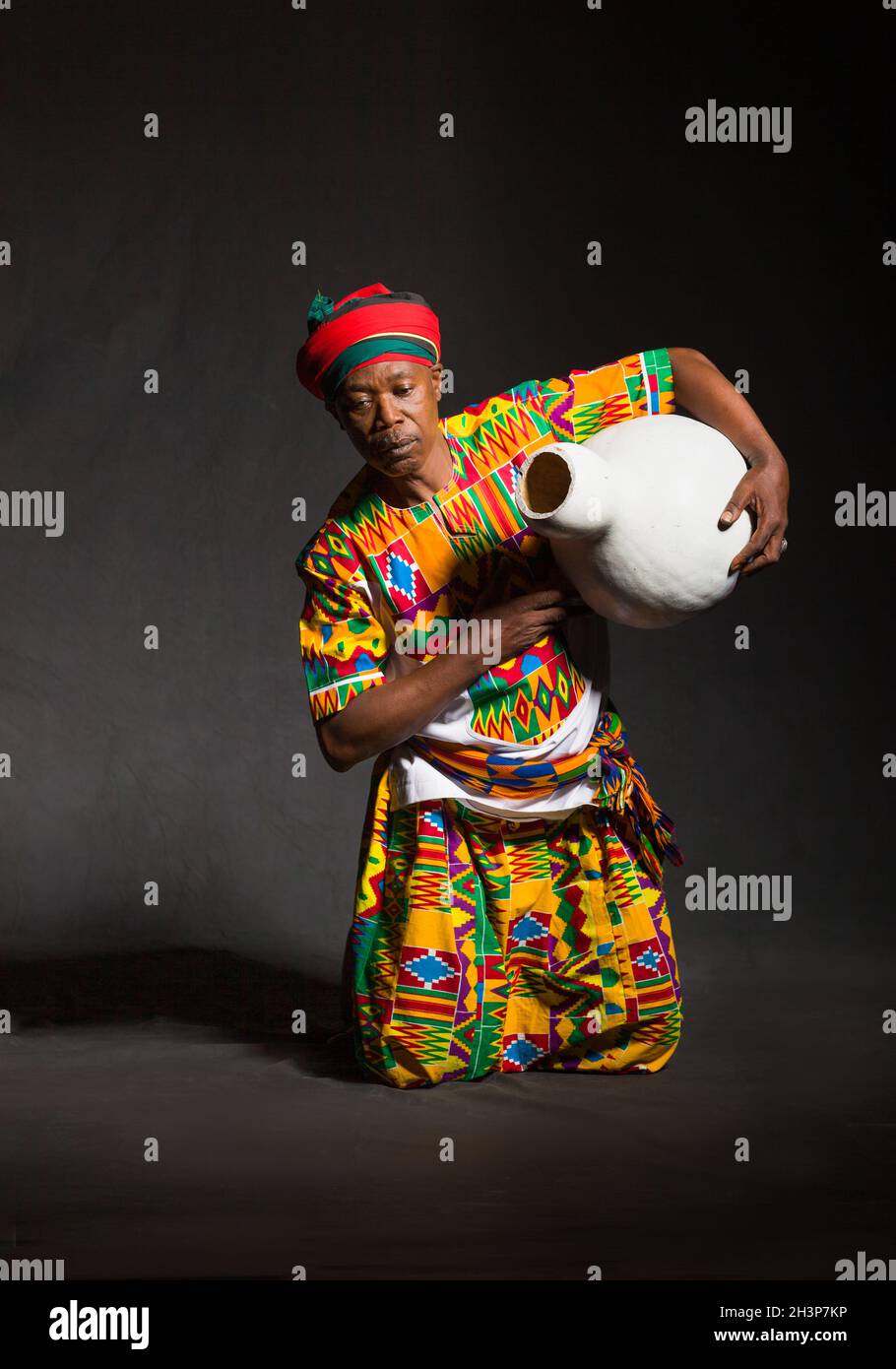 Homme africain dans les vêtements traditionnels souriant, sur fond gris Banque D'Images