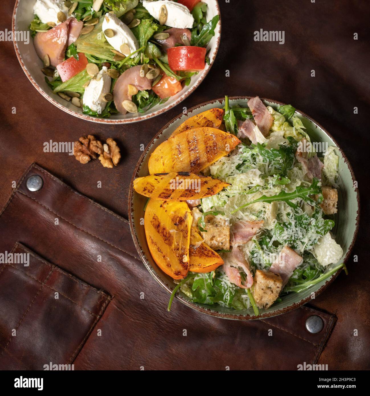 Des salades de saumon au fromage mozzarella et des tranches de fruits grillées se trouvent sur une table recouverte d'un chiffon en cuir.Restaurant conce Banque D'Images