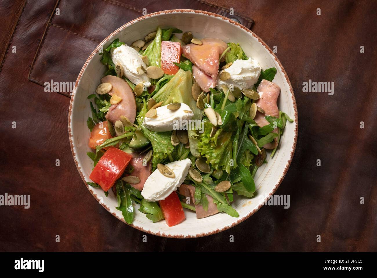Salade de légumes frais au saumon et mozzarella sur une table recouverte d'un chiffon en cuir et d'un détail décoratif d'un si Banque D'Images