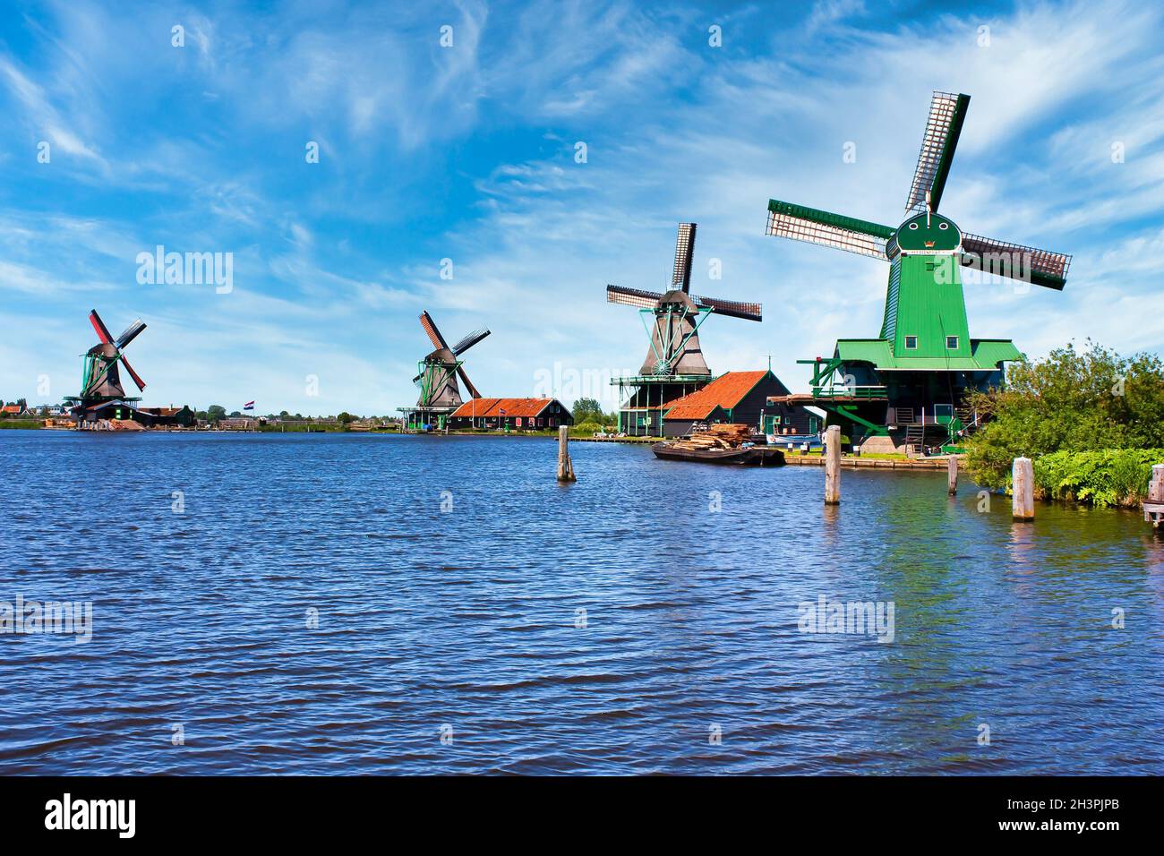 Moulin à vent hollandais dans la campagne verte près d'Amsterdam, pays-Bas, avec ciel bleu et eau de rivière. Banque D'Images