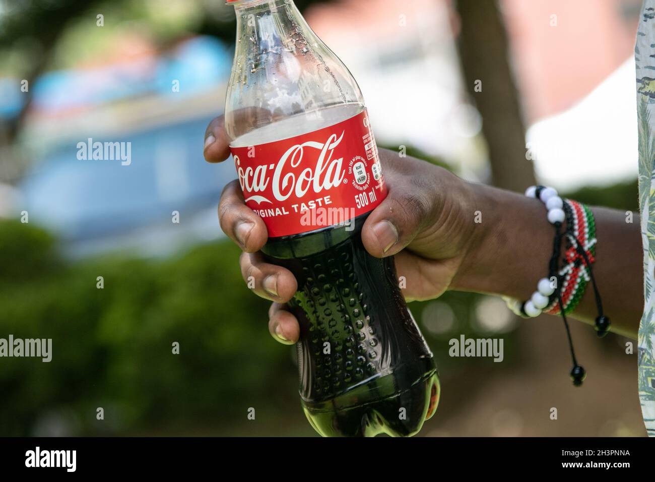Sur cette photo, une main tient une boisson non alcoolisée Coca-Cola.En  moyenne, 38 % des déchets plastiques collectés près du parc national du lac  Nakuru, site classé au patrimoine mondial de l'UNESCO,