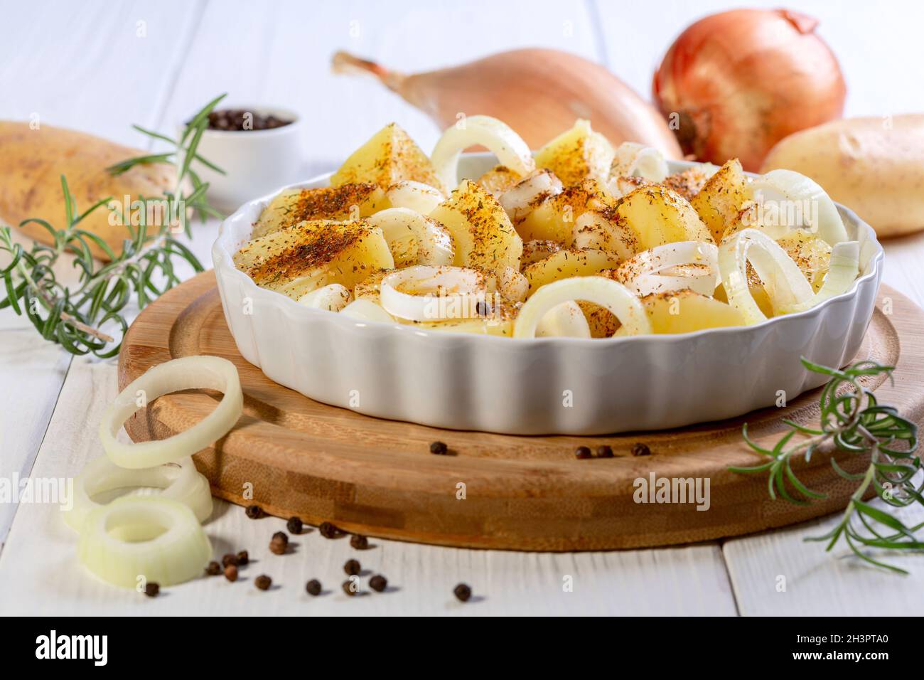 Tranches de pommes de terre crues et oignons aux épices. Banque D'Images