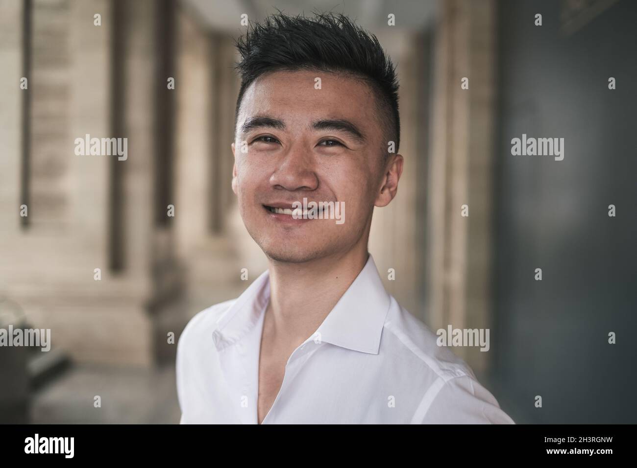 Gros plan Portrait de jeune asiatique beau homme dans des vêtements décontractés debout à l'extérieur et souriant.Chinois, regardant un appareil photo avec un espace de copie Banque D'Images