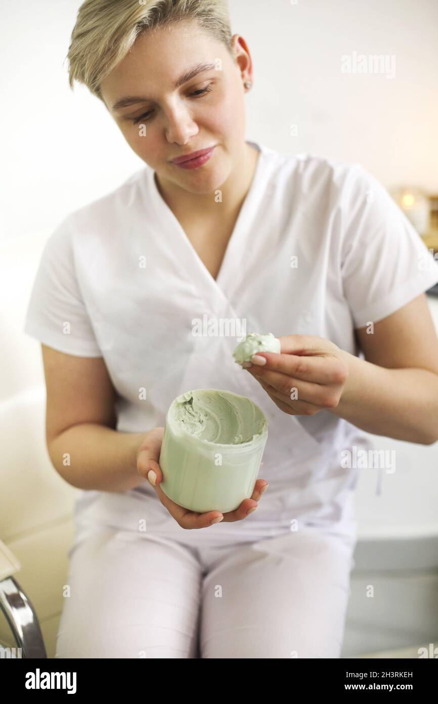 Jeune esthéticienne avec pot de crème en salon Banque D'Images