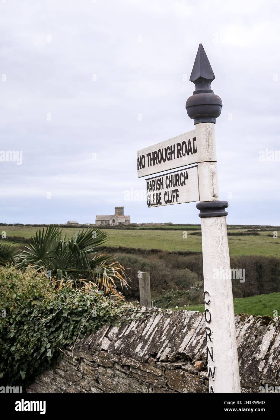 Panneau traditionnel en métal rétro blanc pointant vers le chemin de la falaise et l'église dans le village près de Glebe Cliff dans le sud-ouest de l'Angleterre de Cornwall.Belle campagne Banque D'Images