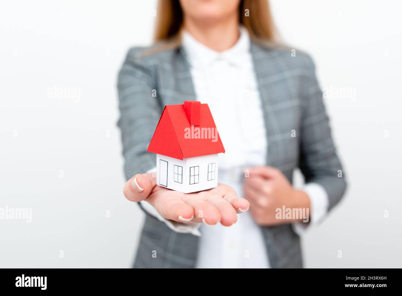 Une dame tenant la maison en tenue d'affaires présentant la possibilité de posséder votre propre immobilier.Acheter une maison ou déplacer une nouvelle Insuran Banque D'Images