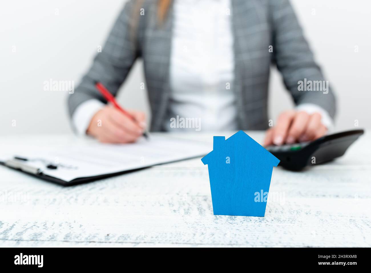 Une dame tenant la maison en tenue d'affaires présentant les calculs possibles pour posséder l'immobilier.Signature d'un nouveau contrat d'assurance Banque D'Images