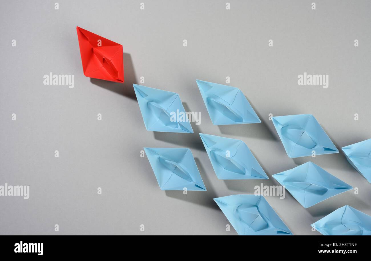 Groupe de bateaux en papier sur fond gris. Concept d'un leader fort dans une équipe, manipulation des masses Banque D'Images