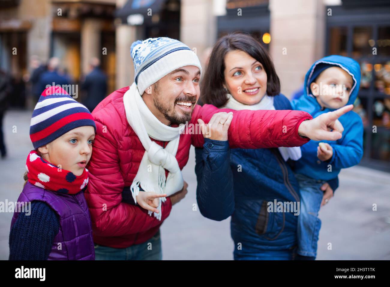 Famille de quatre personnes marchant dans la ville et regardant le showplace Banque D'Images