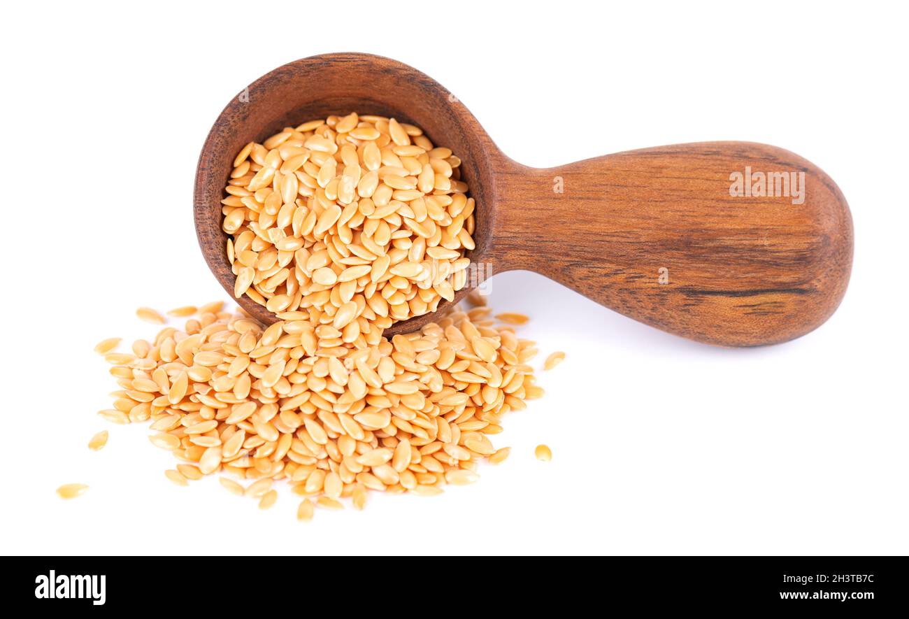 Graines de lin doré en cuillère en bois, isolées sur fond blanc.Tas de graines de lin ou de lin sèches. Banque D'Images