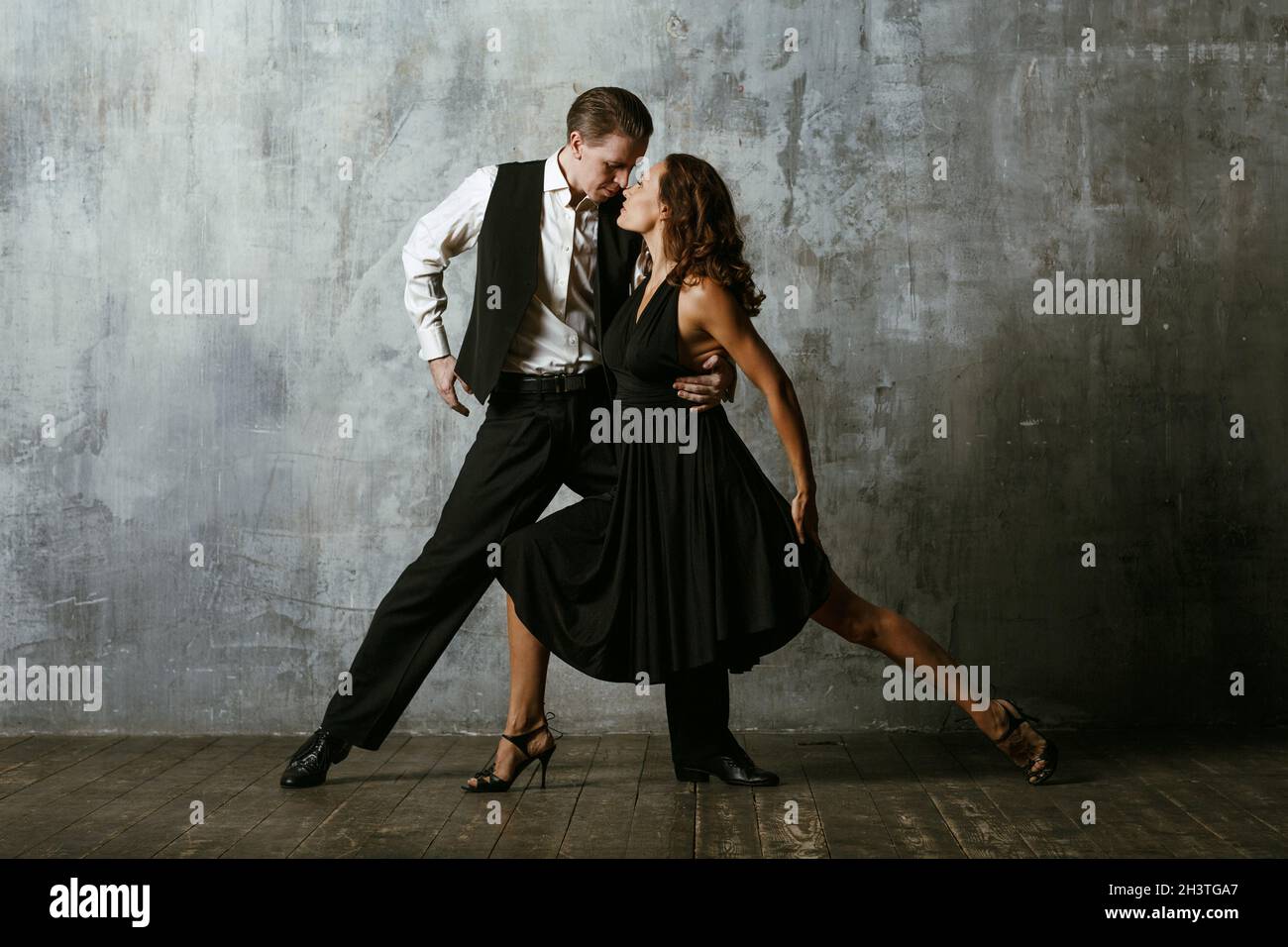Homme et femme danseuses en noir danse tango Banque D'Images
