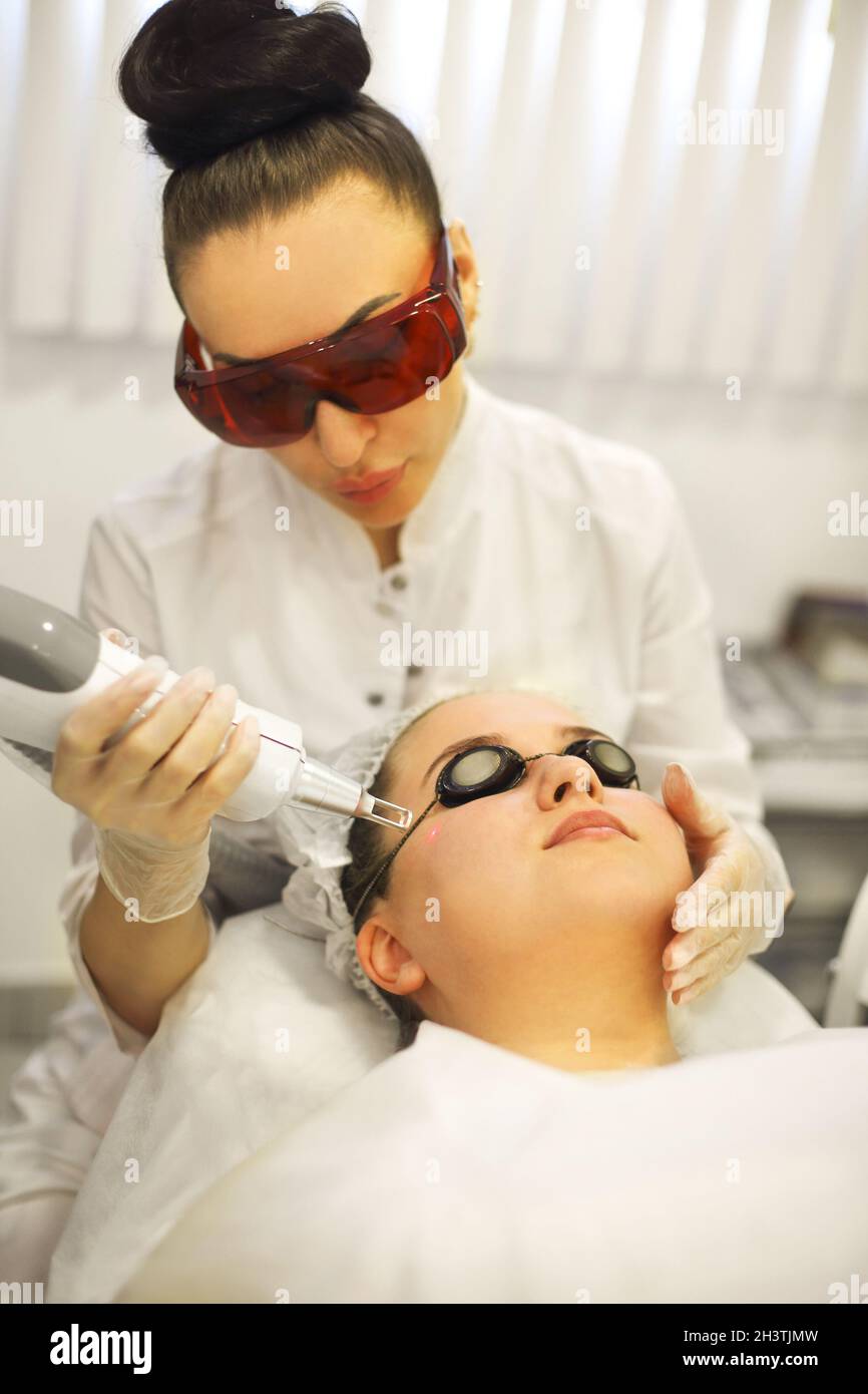 Femme traitant le visage du client au laser Banque D'Images