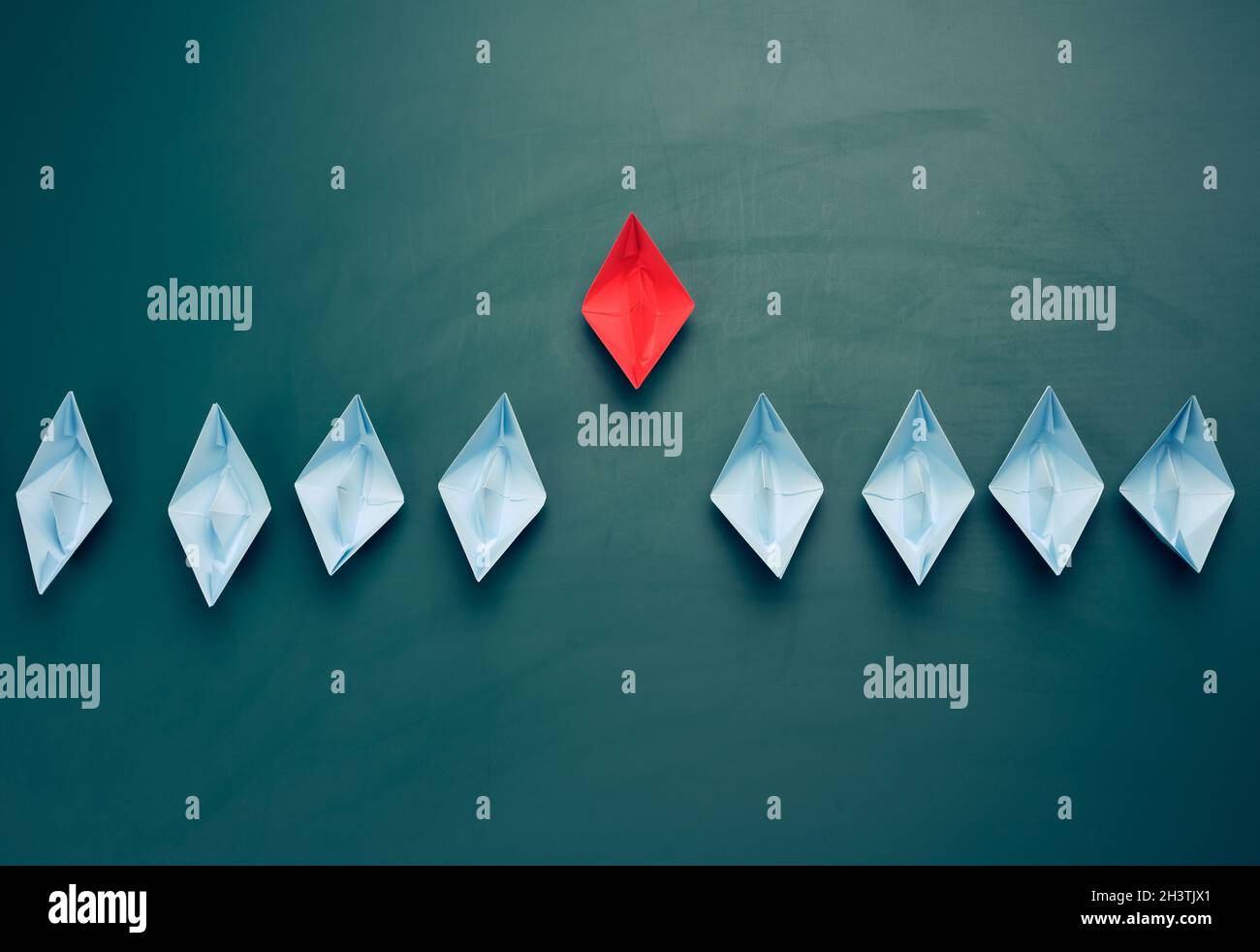 Groupe de bateaux en papier sur fond vert. Concept d'un leader fort dans une équipe Banque D'Images