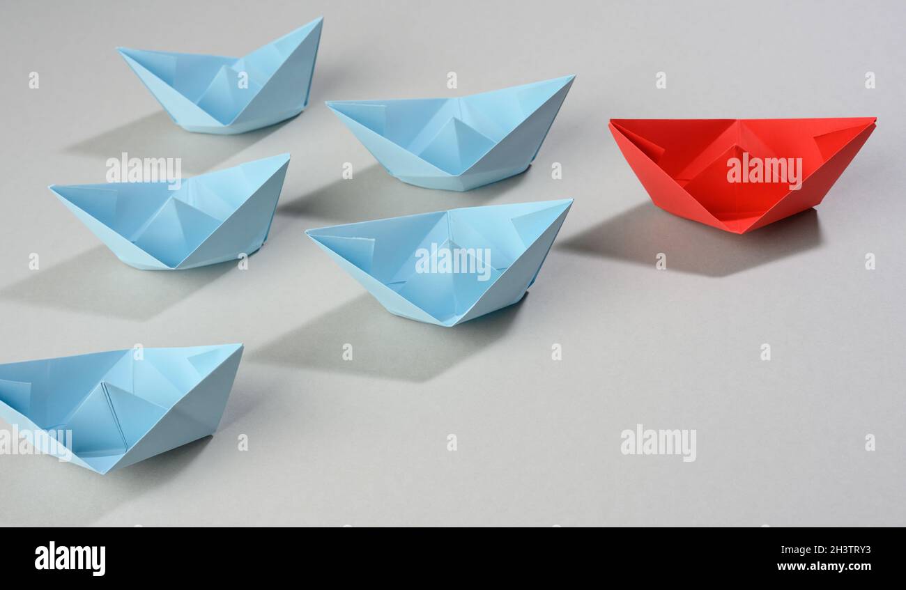 Groupe de bateaux en papier sur fond gris. Concept d'un leader fort dans une équipe, manipulation des masses Banque D'Images