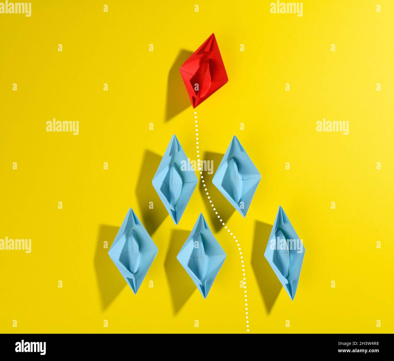 Groupe de bateaux en papier bleu et une LED rouge sur fond jaune. Banque D'Images