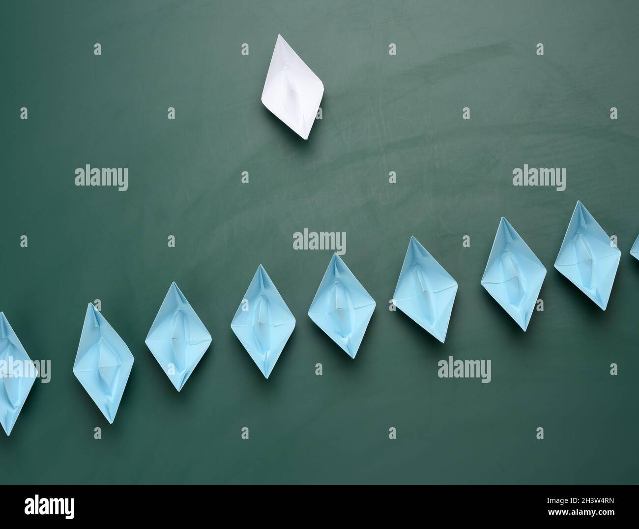 Groupe de bateaux en papier sur fond vert. Concept d'un leader fort dans une équipe, manipulation des masses, suivant de nouvelles pers Banque D'Images