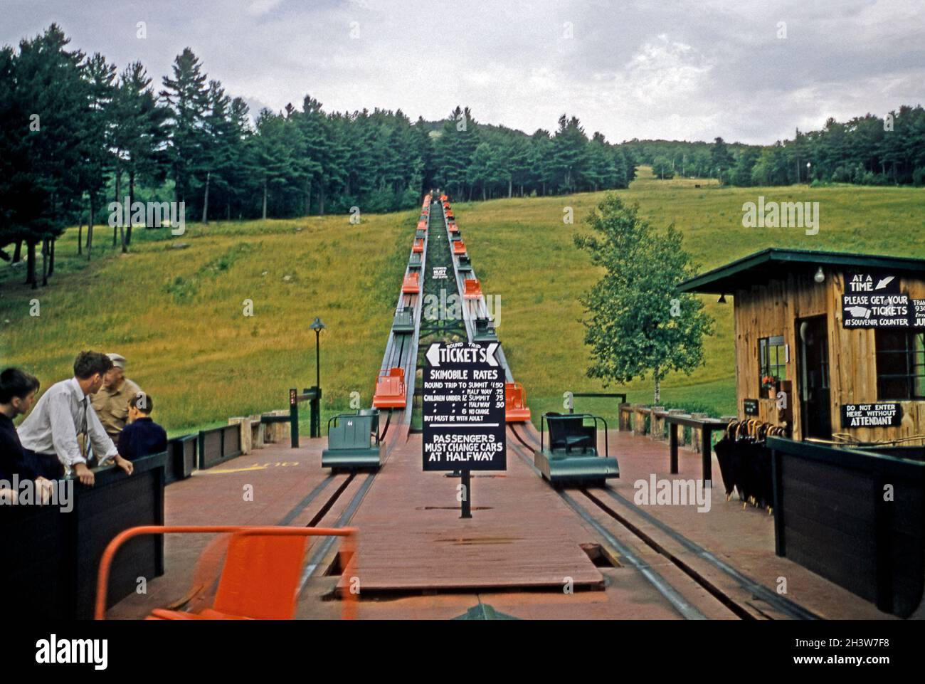 Le parcours de passagers SkimMobile, le domaine skiable de Mount Cranmore, North Conway, New Hampshire, États-Unis à sa base pendant les mois d'été dans les années 1950.Cet ascenseur était une construction en chevalet avec des voitures en métal colorées transportant chacune un passager tiré par un câble sous les voies dans une boucle continue de haut en bas de la montagne.Le panneau indique un aller-retour au sommet pour 1.50 $.Il a été remplacé par un ascenseur classique en 1989.Cette image est tirée d'une ancienne transparence couleur Kodak amateur américaine, une photographie vintage des années 1950. Banque D'Images