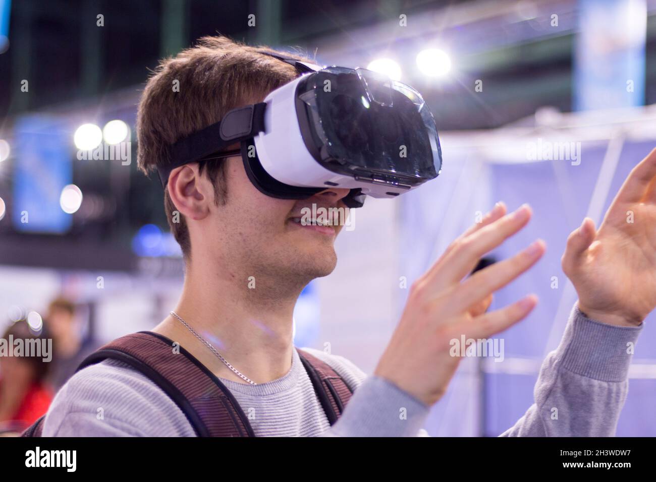 Un jeune homme portant des lunettes de réalité virtuelle lors d'une exposition s'amuse Banque D'Images