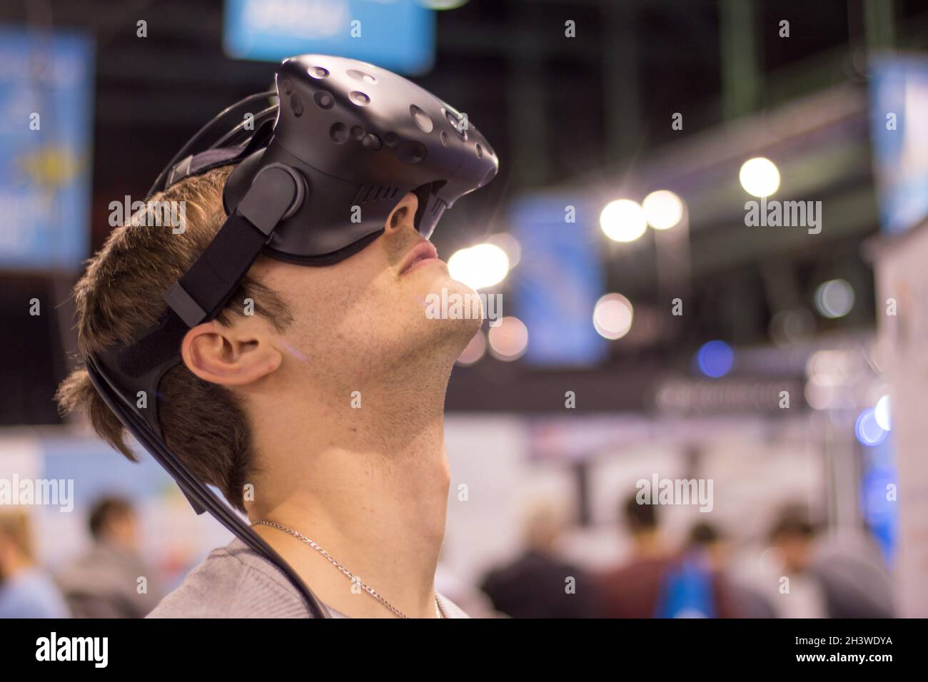 Un jeune homme portant des lunettes de réalité virtuelle lors d'une exposition s'amuse Banque D'Images
