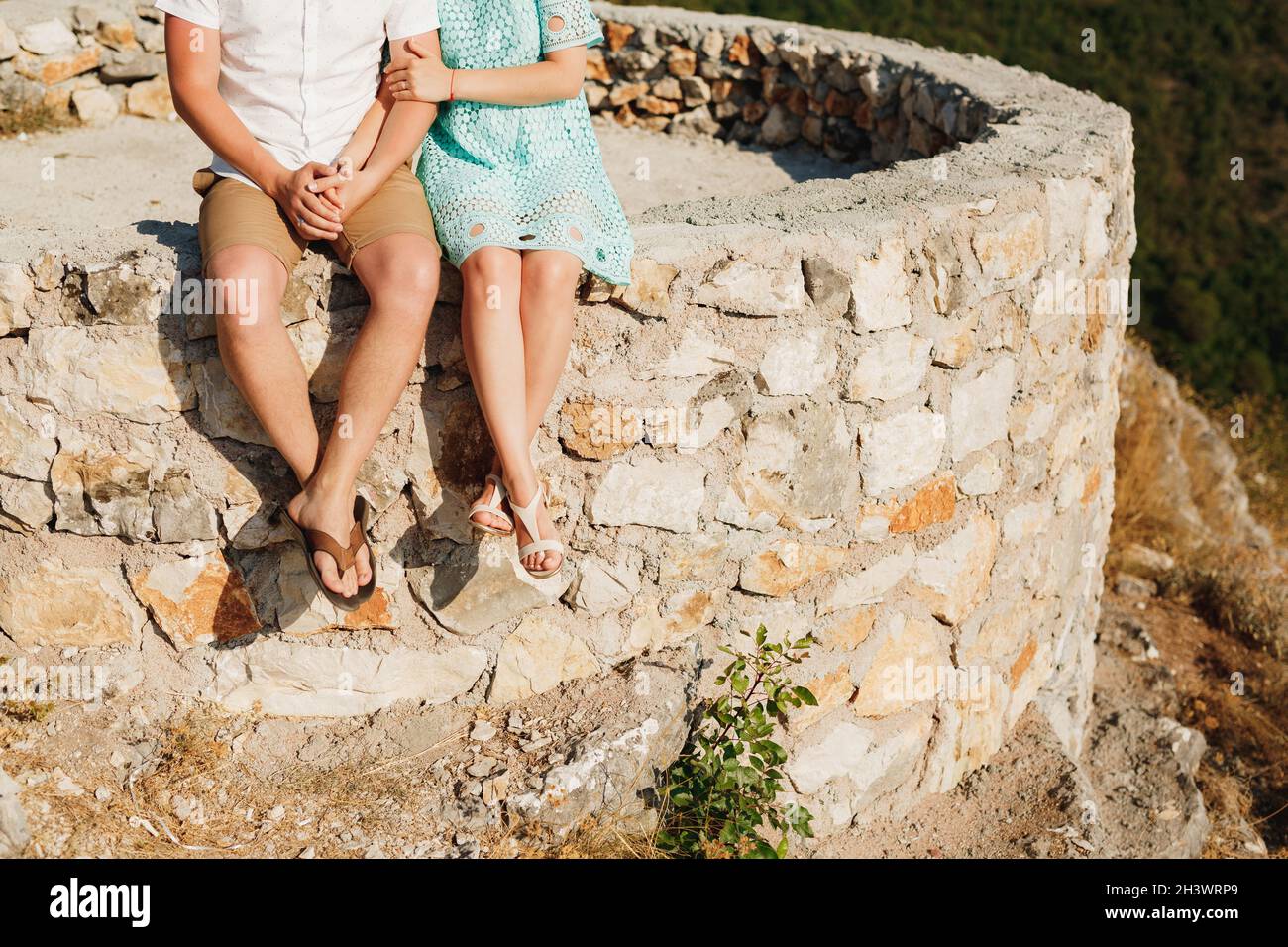 Un homme et une femme sont assis côte à côte sur le bord d'une plate-forme en pierre Banque D'Images