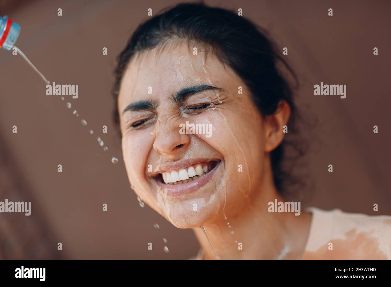 Femme stressée souffrant d'un coup de chaleur rafraîchissant avec de l'eau froide à l'extérieur.Concept de chaleur anormale par temps. Banque D'Images