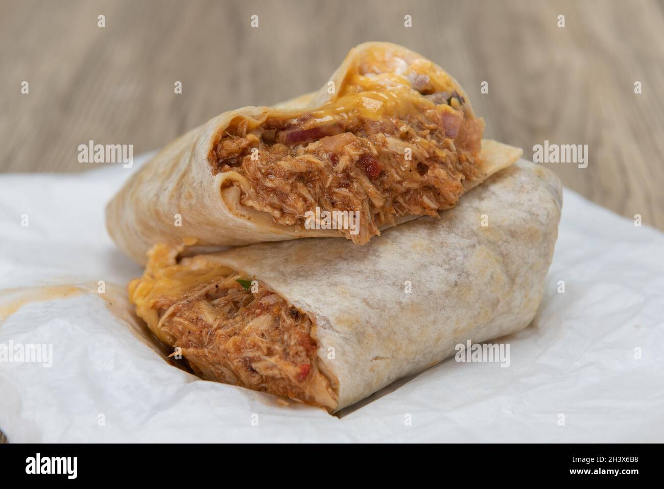 Délicieux et copieux petit déjeuner de poulet râpé burrito coupé en moitié pour montrer les ingrédients éclatés. Banque D'Images