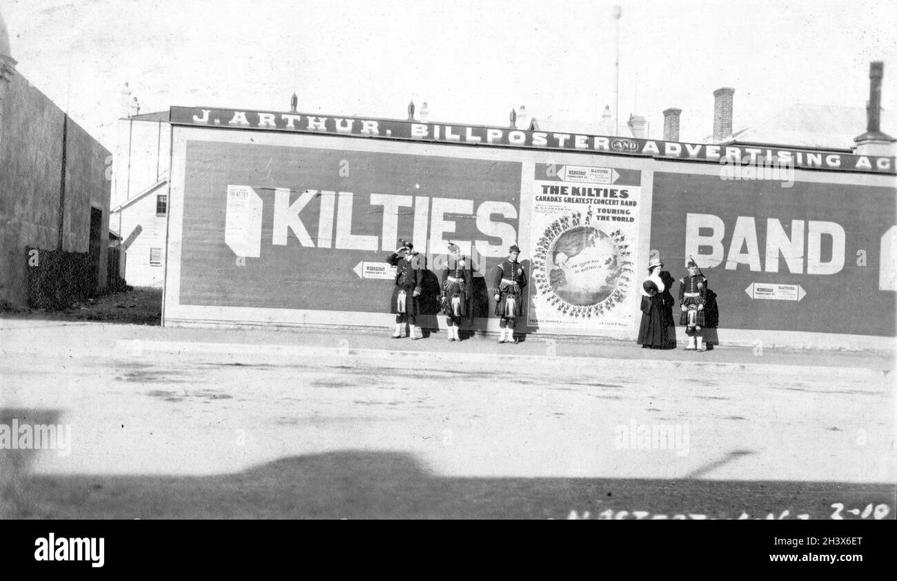 Certains membres de The Kilties, une bande canadienne d'Écossais, se tiennent à côté de la publicité à Masterton, en Nouvelle-Zélande, pendant leur tournée mondiale, 1909. Banque D'Images