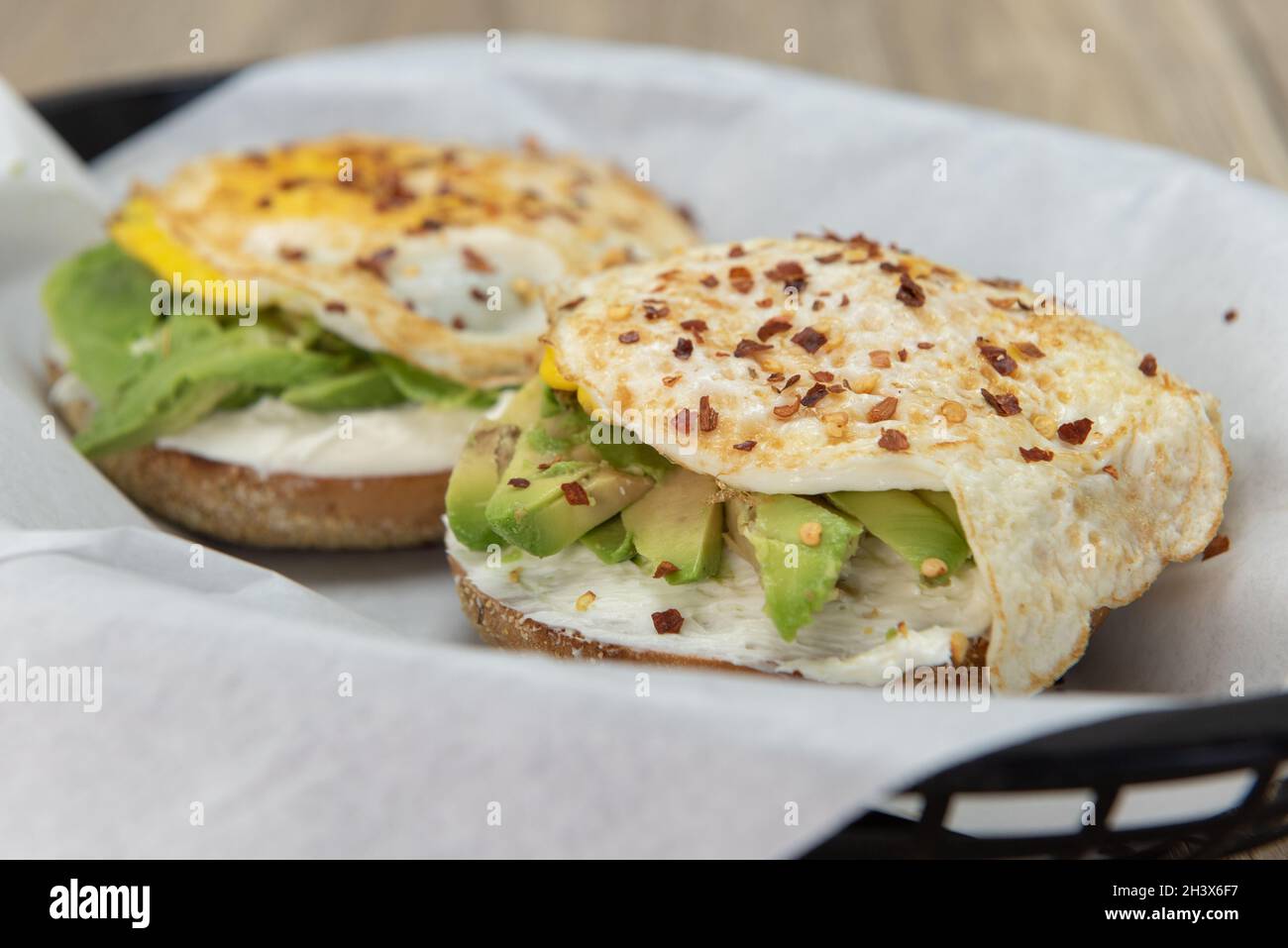 Petit déjeuner savoureux et copieux, garni d'avocat et d'œufs frits parsemés de flocons de poivre. Banque D'Images