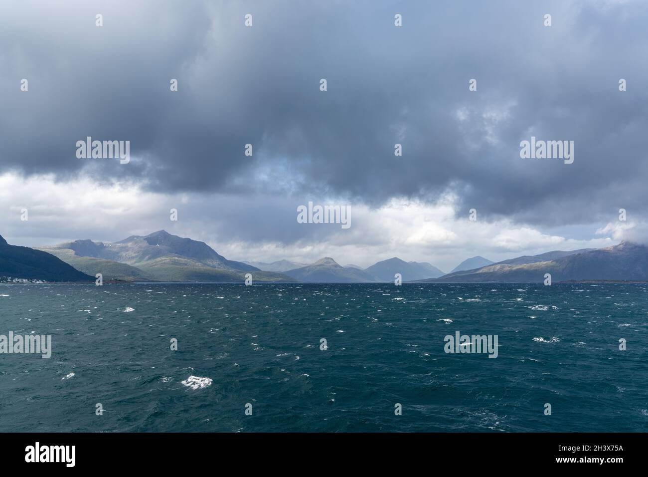 Une côte sauvage et sauvage avec des montagnes et des mers orageux avec des whitecaps sous un ciel nuageux et expressif Banque D'Images