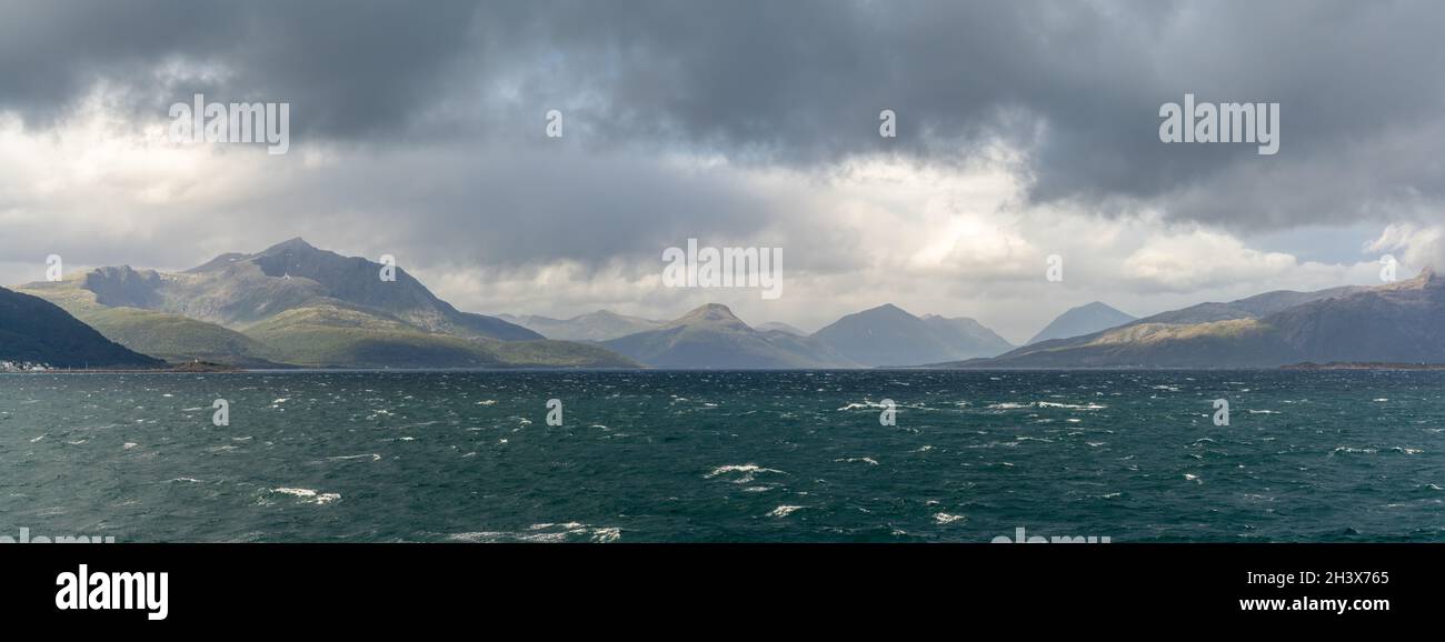 Une vue panoramique sur une côte sauvage et sauvage avec des montagnes et des mers orageux avec des whitecaps sous un ciel nuageux et expressif Banque D'Images