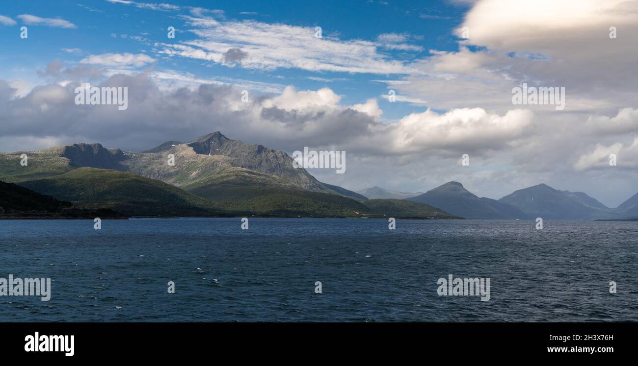 Une vue panoramique sur une côte sauvage et sauvage avec des montagnes et des mers orageux avec des whitecaps sous un ciel nuageux et expressif Banque D'Images