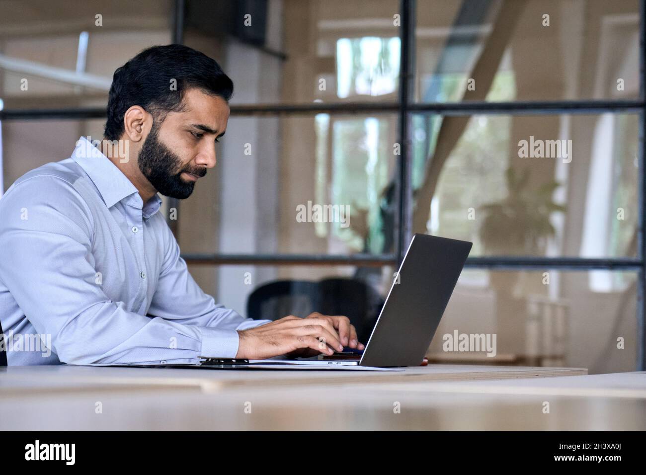Un homme d'affaires originaire d'Inde latine travaille dans un bureau moderne avec un ordinateur portable. Banque D'Images