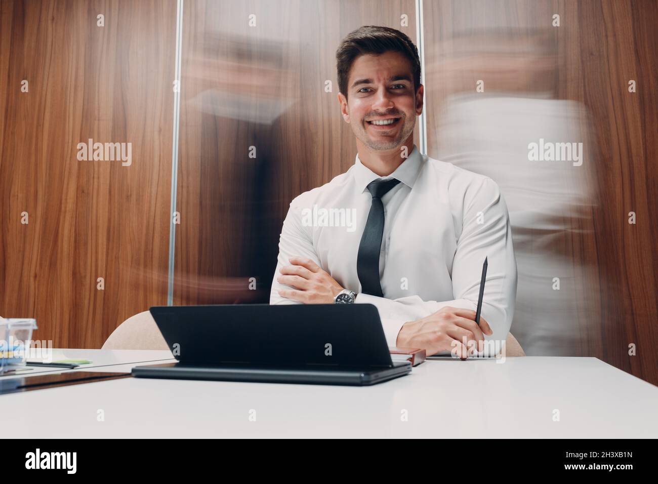 Homme d'affaires utilisant un ordinateur portable s'asseoir à table dans le bureau de réunion avec des personnes marchant avec le flou de mouvement.Hommes d'affaires et Banque D'Images