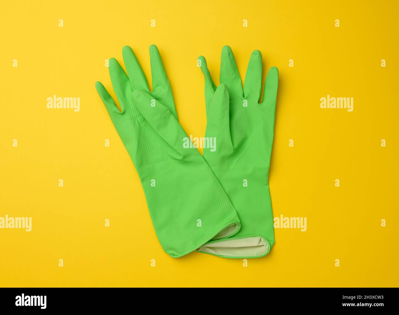 Paire de gants de protection en caoutchouc vert pour le nettoyage sur fond jaune Banque D'Images