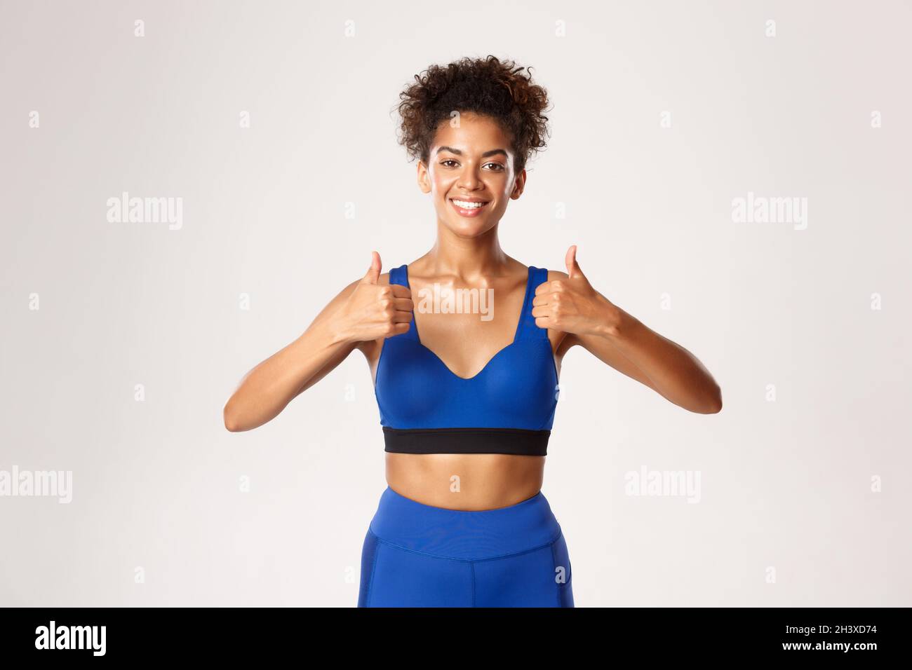 Taille haute de la magnifique femme de fitness afro-américaine, portant une  tenue de sport bleue, montrant le pouce vers le haut dans l'approbation,  recommander l'équipement f Photo Stock - Alamy