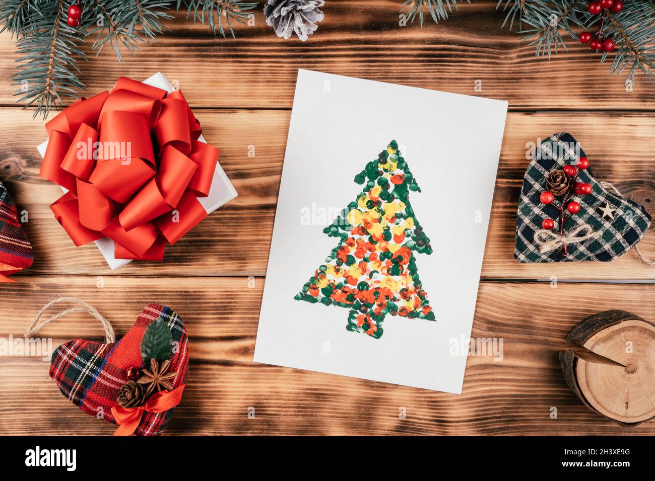 Arbre de Noël en carton fait main carte de vœux faite avec des empreintes  digitales des enfants sur fond de bois avec des branches de sapin et des  décorations de Noël.Haut Photo