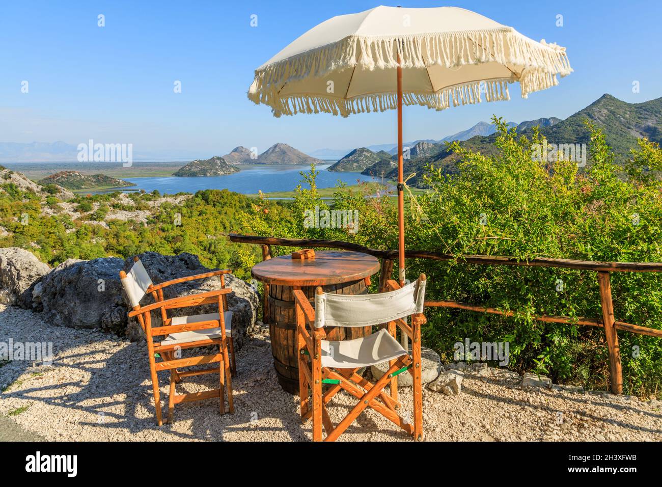 Vue panoramique sur le lac de Skadar et les montagnes depuis la route café avec tables, chaises et parasols, Monténégro Banque D'Images