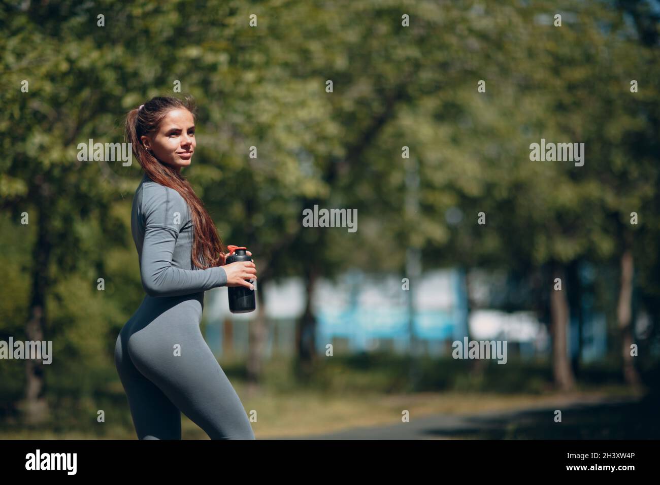 Femme de chemin fatiguée jogger boire de l'eau en bouteille après avoir fait du jogging dans le parc à l'extérieur. Banque D'Images