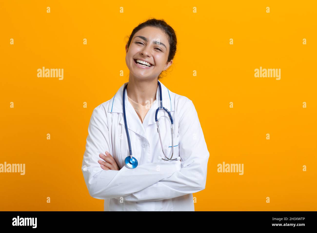 Portrait d'une femme médecin indienne en robe médicale blanche isolée sur fond jaune Banque D'Images
