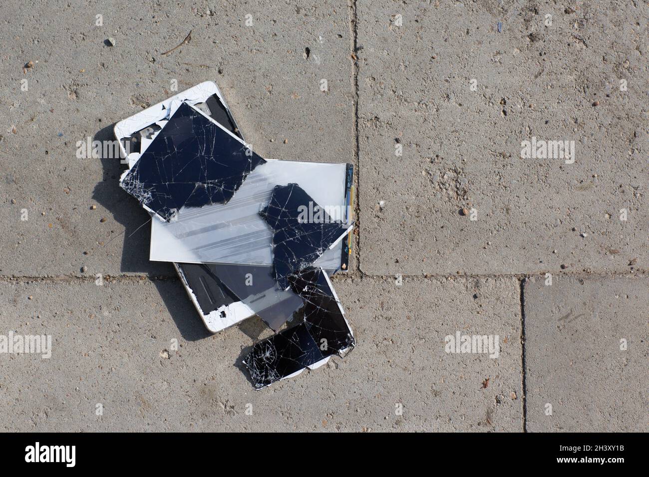 Un téléphone portable à écran cassé est au sol. Banque D'Images