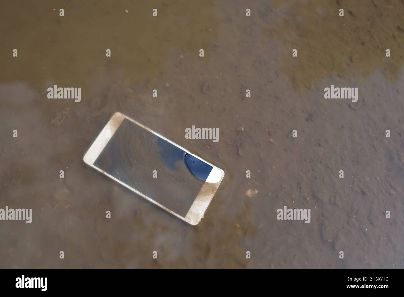 Téléphone mobile couché sur la chaussée dans la flaque. Banque D'Images