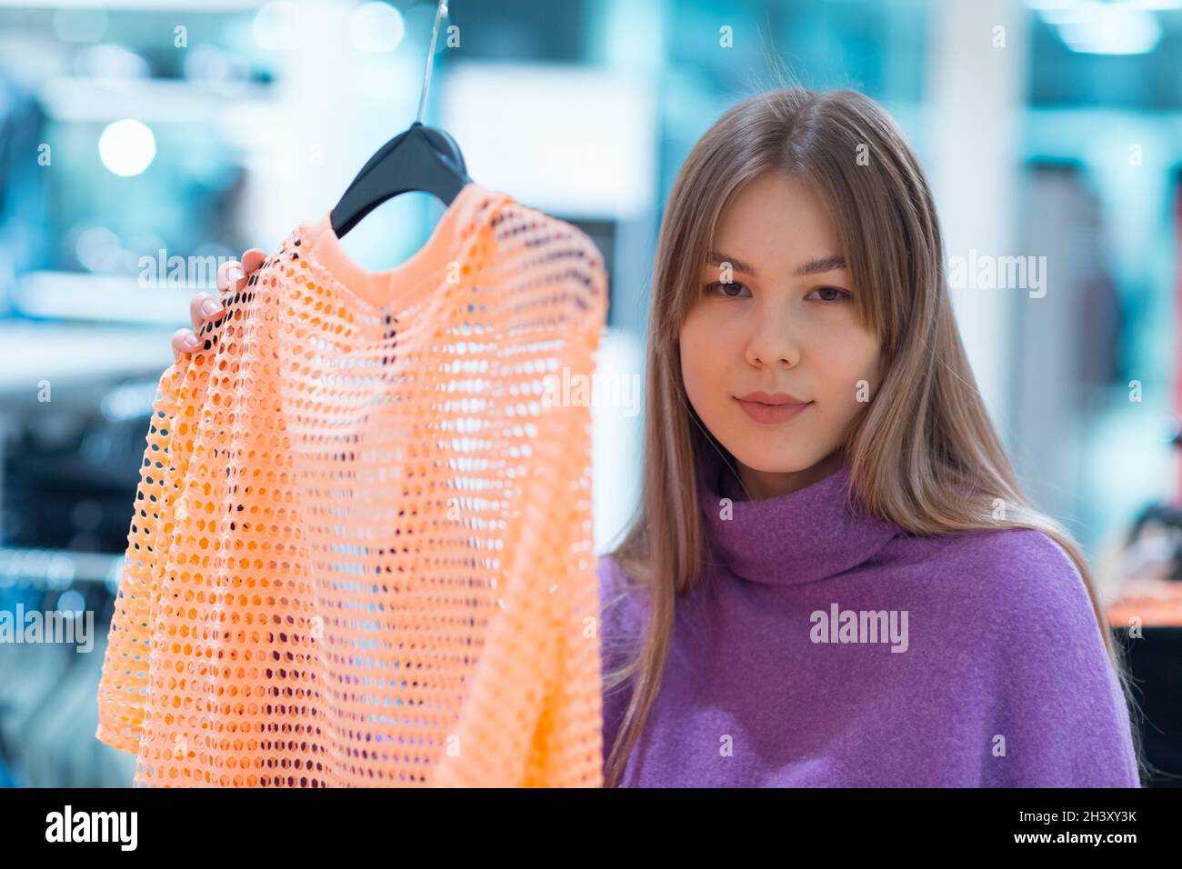 Une jeune femme choisit des vêtements dans un magasin Banque D'Images