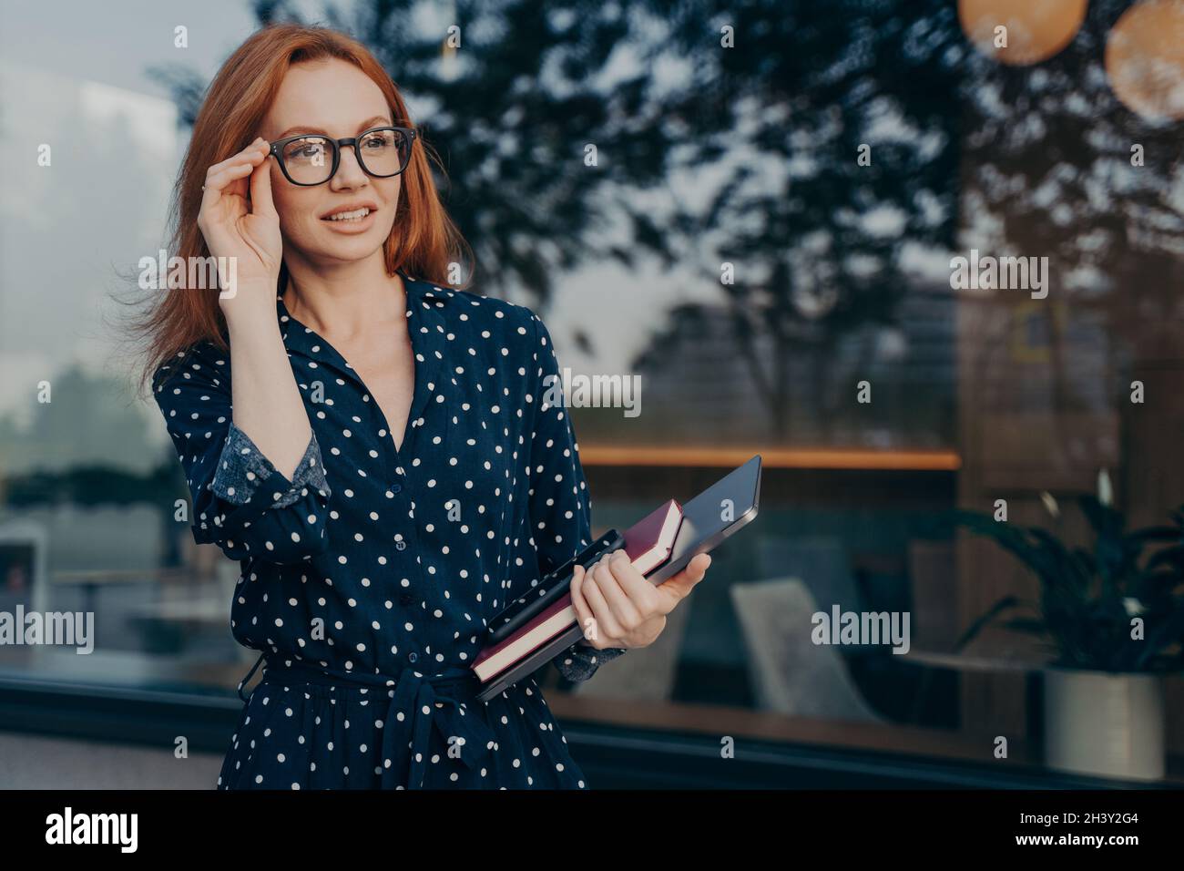 L'entrepreneur féminin porte une tablette smartphone et une vitrine d'organisateur près de la fenêtre du restaurant Banque D'Images
