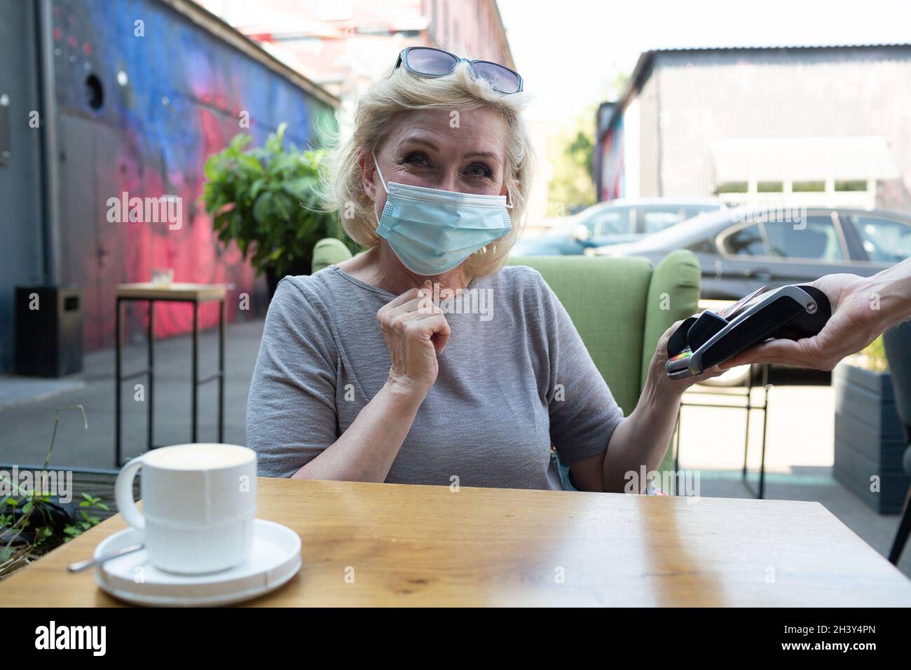 Une femme âgée paie avec une carte de crédit, un guichet de paiement sans contact, dans un café en plein air Banque D'Images