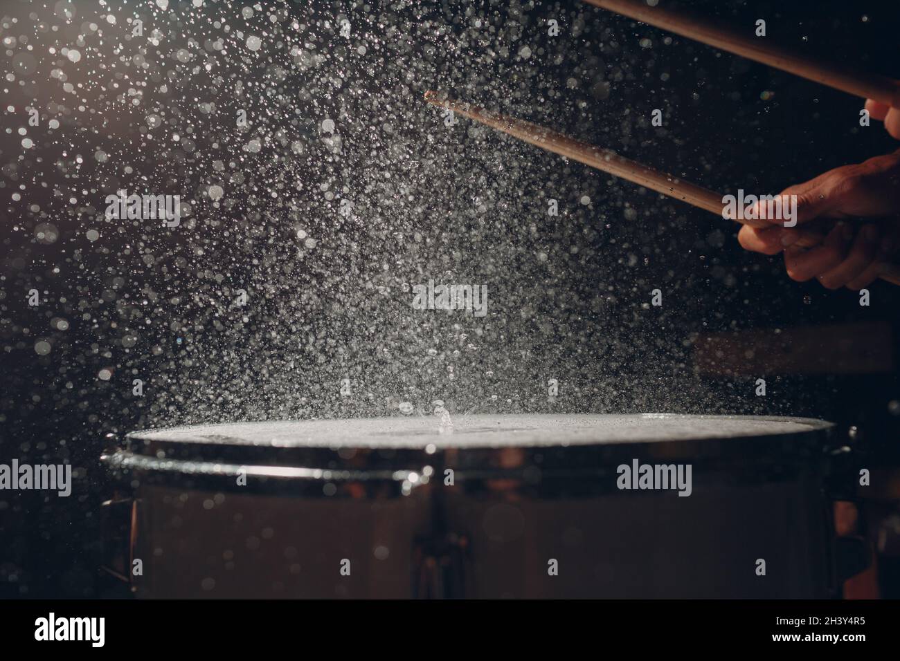 Bâtonnets de batterie rythme de rythme de rythme sur la surface du tambour avec gouttes d'eau Banque D'Images