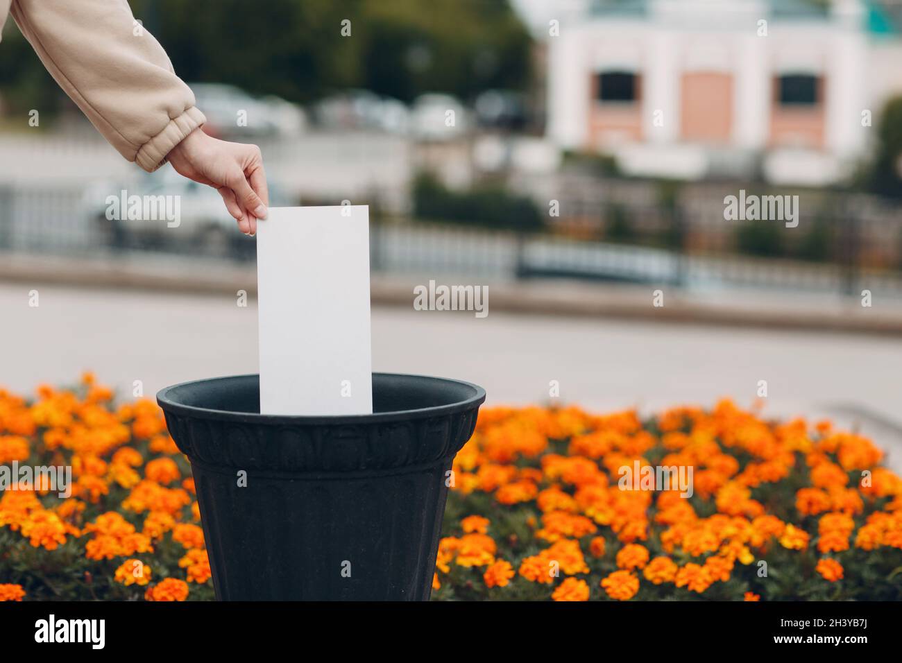 La femme jette une feuille de papier blanc sans inscription dans la poubelle.Modèle pour les mots avec espace de copie. Banque D'Images