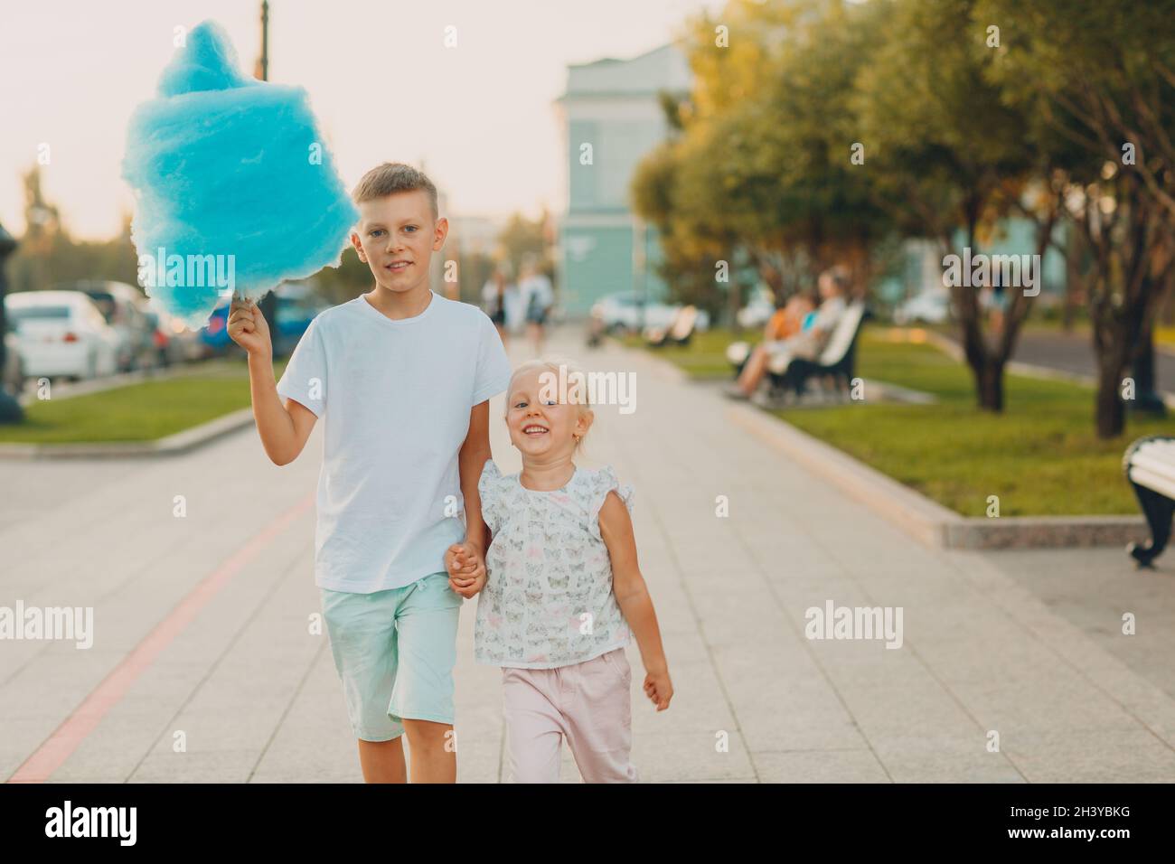 Les enfants heureux garçon et fille mangeant des bonbons en coton bleu à l'extérieur Banque D'Images